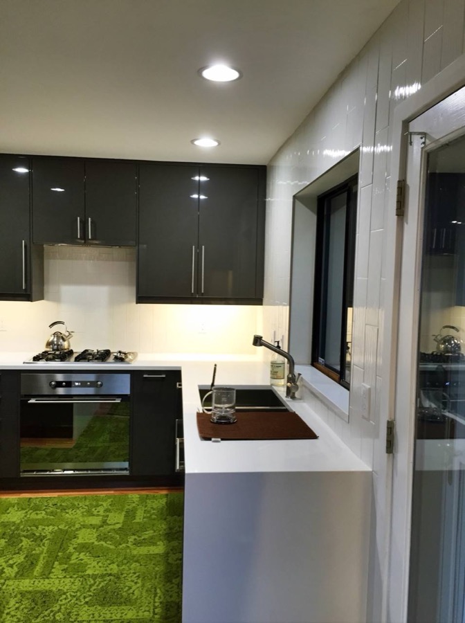 Finished kitchen with glossy dark cabinets and white tile